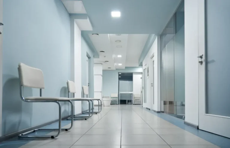 Modern hallway in a medical coworking space with white chairs and private consultation rooms.