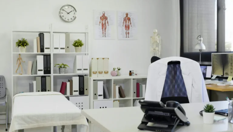 Well-organized medical office space with anatomical charts, shelving, and examination table in a professional healthcare setting